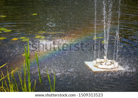 Rainbow on the river with an artificial fountain