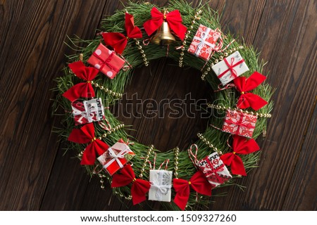 Christmas wreath decorated with red bows, Christmas bell and small gift boxes 