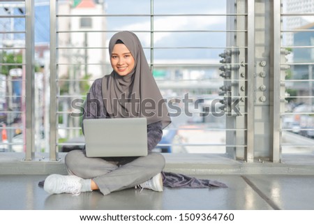 Asian muslim woman sitting with laptop computer.