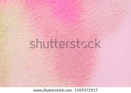 Many multi-colored spangles are scattered on a pink background.  View from above.  Place for text.