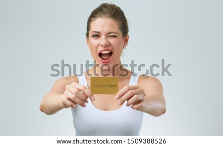 winking woman in white casual vest holding credit card in front of. isolated portrait.