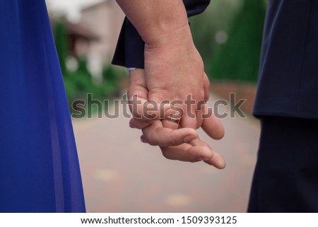 Newlyweds hold hands with rings and a bouquet on the wedding day