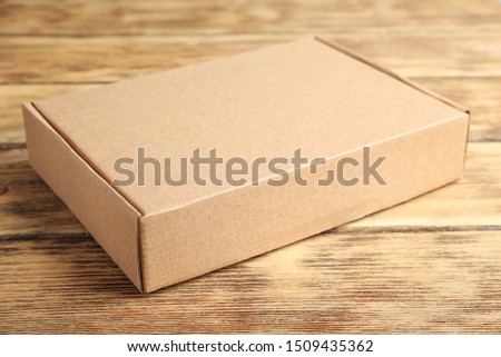 Closed cardboard box on brown wooden table