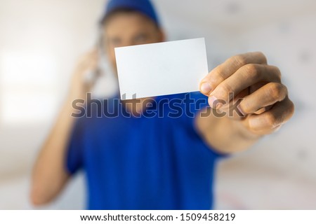 handyman services - worker showing blank business card and making a phone call