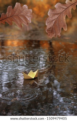 oak leaves, paper boat in water, abstract natural autumn background. fall season. sadness melancholy atmosphere image. autumn rain season. symbol of travel, adventure, dreams. 