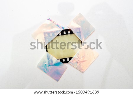 real macro photo of empty and blank 35mm filmstrip on white paper background with holo stickers on border edges, blend in your photo here, cool photo placeholder, shiny cellotape on film  Royalty-Free Stock Photo #1509491639