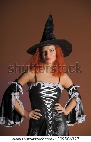 Young woman with red hair in withch costume on dark orange background