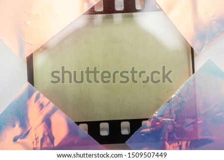 real macro photo of empty and blank 35mm filmstrip on white paper background with holo stickers on border edges, blend in your photo here, cool photo placeholder, shiny cellotape on film Royalty-Free Stock Photo #1509507449