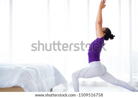 Healthy female practicing morning yoga in bedroom. Beginner yoga woman is in sun salutation yoga pose. The position required stretching & balance. The flexibility exercises is for health & wellness.  