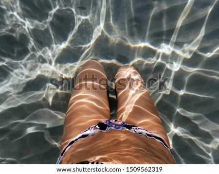 Underwater picture of a young woman lying down on the beach shore