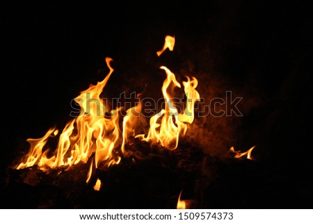 The flame is burning with a scattering heat energy on a black background.