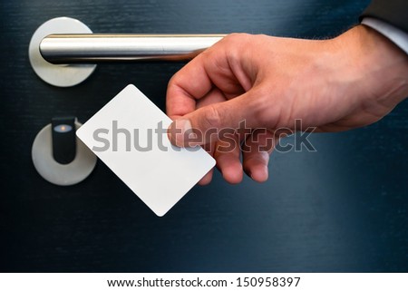 Hotel door - Young man holding a keycard in front of the electronic sensor of a room door  Royalty-Free Stock Photo #150958397
