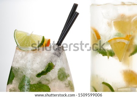 Glass and pitcher of lemonade with lemon, lime and mint on white background.  Soda water with citrus and ice. Lime and orange in sparkling water             