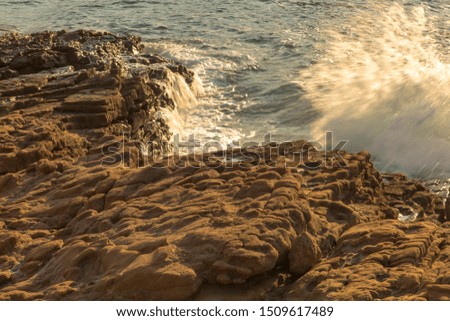 View of foam with white waves, foam of blue sea and rocks. Nature, sea concept. Horizontal close-up shot.