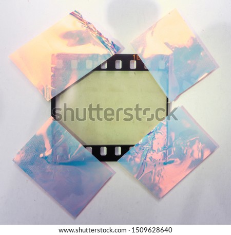 real macro photo of empty and blank 35mm filmstrip on white paper background with holo stickers on border edges, blend in your photo here, cool photo placeholder, shiny cellotape on film Royalty-Free Stock Photo #1509628640