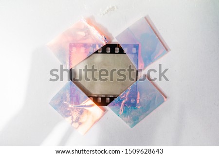 real macro photo of empty and blank 35mm filmstrip on white paper background with holo stickers on border edges, blend in your photo here, cool photo placeholder, shiny cellotape on film Royalty-Free Stock Photo #1509628643