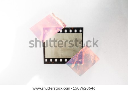 real macro photo of empty and blank 35mm filmstrip on white paper background with holo stickers on border edges, blend in your photo here, cool photo placeholder, shiny cellotape on film Royalty-Free Stock Photo #1509628646