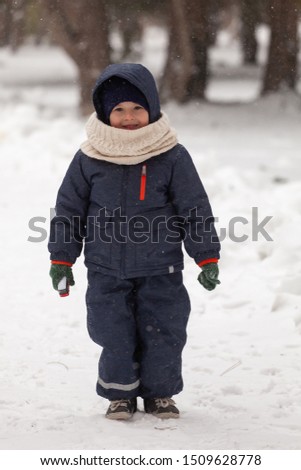 Happy little boy at the park in winter snow