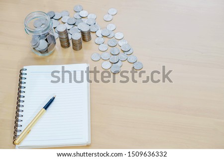 notebook with a pen and a pile of coins 