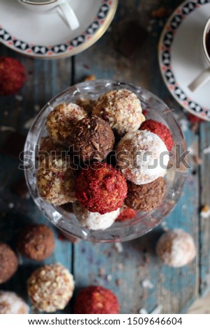 Homemade candies with nuts, coconut flakes, chocolate and dried strawberry on a blue wooden background. Tea party with candies nobody. Flat lay, top view. Rustic style