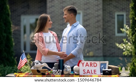 Couple selling second hand things on yard sale and looking at each other, fun