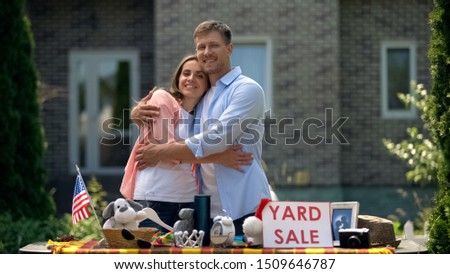 Happy couple selling old things on yard sale and hugging, american traditions