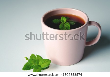A cup of tea with mint on white table. Isolated object.
