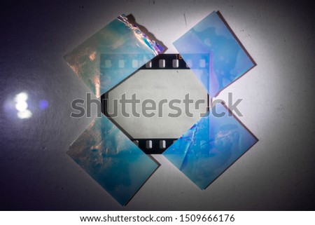 bright lamp is shining on real blank 35mm film frame strip fixed on white paper background with 4 shiny holo stickers, cool photo placeholder for your content