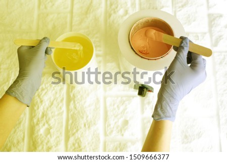 hot pink wax in white bowl for Hair removal and paste for sugaring with hands on white background. closeup. Beauty Concept. Toned