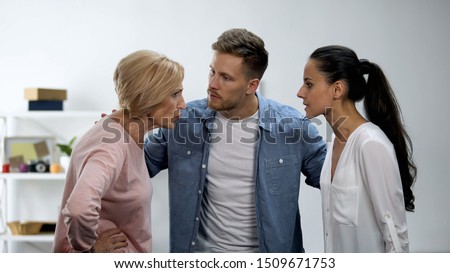 Man trying to calm wife and mother arguing, in-law conflict, troubled marriage Royalty-Free Stock Photo #1509671753