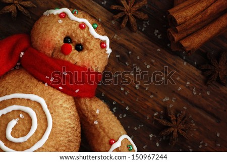 Gingerbread man (ornament made of fabric to look like a cookie) on rustic, dark wood background with sugar and spices.  Macro with shallow dof. 