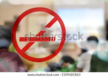 no smoking sing sticker on the glass door with blurred people in meeting room