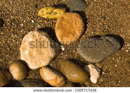 Colorful stones standing on the sand at the beach. Sea, vacation, stones concept. Horizontal close-up shot.