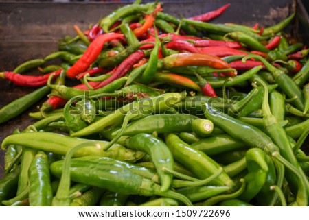 Green and red chili on a counter top of a store during food festival market. Fresh and raw stack of green peppers, authentic spicy mexican ingredient for many dishes. Produce for sale