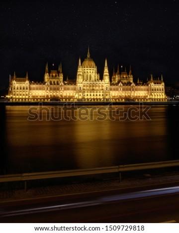 A night picture of the glowing Parliament of Budapest along the Danube river. 