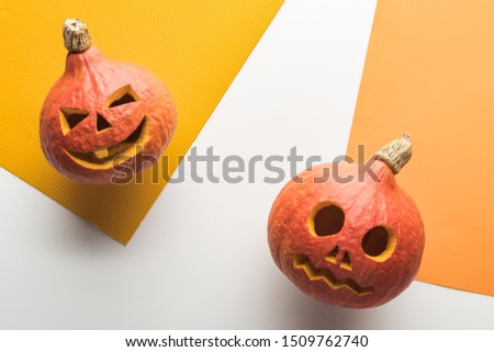 top view of Halloween pumpkins on white and orange background