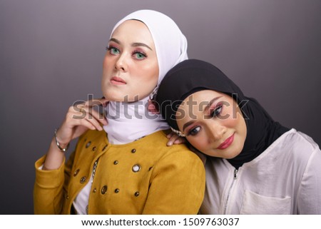 Close up portrait of a beautiful Muslim female models with hijab isolated over grey background. Studio fashion and beauty make up concept.