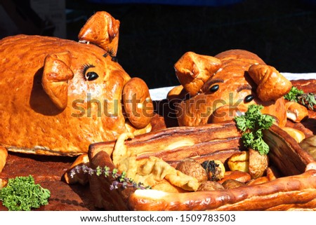 Pig-shaped meat pie. Pig-shaped cakes with french fries and grilled sausages. Festive table decoration.