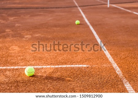 Tennis clay court with balls and net in the background.