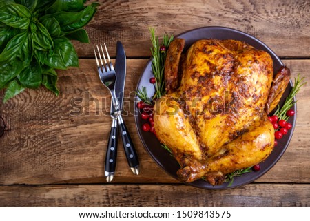 Baked chicken or turkey with herbs for festive dinner on wooden table. Christmas, Thanksgiving Day, holidays concept. Top view, copy space