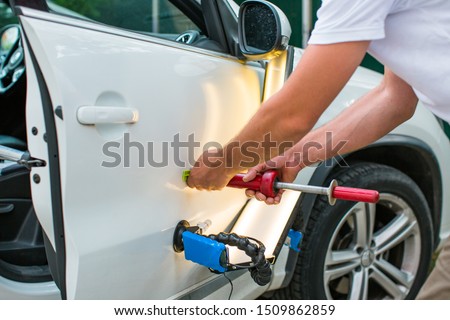 Repairing car dent after the accident by paintless dent repair Royalty-Free Stock Photo #1509862859