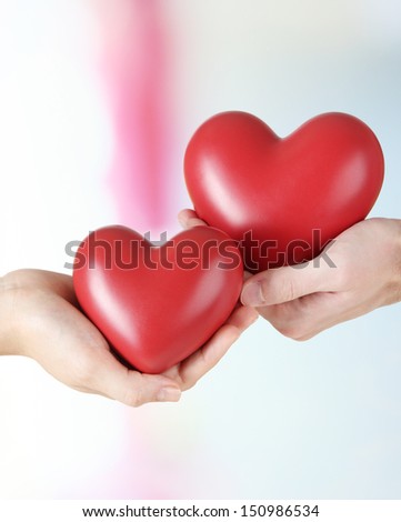 Hearts in hands on light background