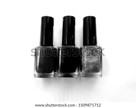 Three nail polishes. Photo in gray tones.