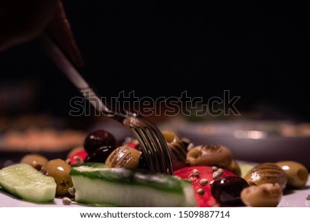 Tomatoes, cucumbers and olives with a fork