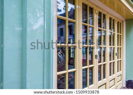 colorful facade with pastel green walls and pastel yellow doors windows and reflections in the glass windows in the pastel painted doors