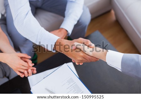 Salesman shaking hands with client with contract on the coffee table Royalty-Free Stock Photo #150995525