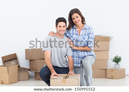 Portrait of a woman and her husband wrapping a box while they are moving home