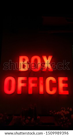 BOX OFFICE SIGN with red light on a wall at night