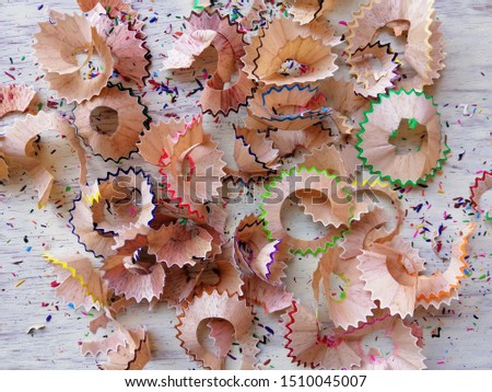 Color pencil shavings on white wooden background 