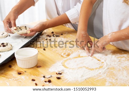 Partial side view of a child drawing a heart symbol in flour on a table, mothers day concept